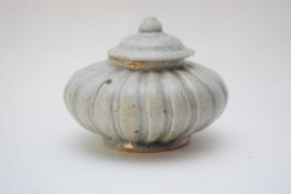 Small pottery jar and cover of compressed form with a ribbed design