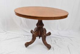 Victorian oak loo table, the oval top supported on a heavy column and quatre base with casters,