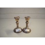 PAIR OF SMALL SILVER CANDLESTICKS WITH LOADED CIRCULAR BASES
