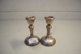 PAIR OF SMALL SILVER CANDLESTICKS WITH LOADED CIRCULAR BASES