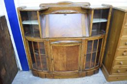 1930S OAK VENEERED COMBINATION BUREAU AND DISPLAY CABINET WITH A BOWED FRONT, 121CM WIDE