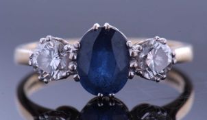 Sapphire and diamond three stone ring, the oval faceted sapphire 8 x 5 x 3.8mm, flanked by two round
