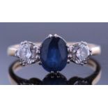 Sapphire and diamond three stone ring, the oval faceted sapphire 8 x 5 x 3.8mm, flanked by two round