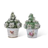 Two Derby porcelain flower pots with ceramic flowers above, the bases also with floral decoration (