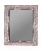 Late Victorian silver mounted dressing table mirror, the edge embossed with scrolls and floral