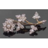 Precious metal diamond set floral spray brooch, the flower head and leaves decorated throughout with