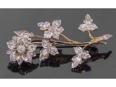Precious metal diamond set floral spray brooch, the flower head and leaves decorated throughout with