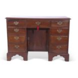 George III mahogany kneehole desk, the body with nine drawers and a central door fitted with brass