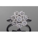 Precious metal and diamond cluster ring featuring seven round brilliant cut diamonds, diamond