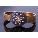 Early 20th century enamel and seed pearl hinged bracelet, the top section with chased and engraved