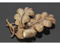 Acorn and oak leaf brooch highlighted with a small round cut sapphire with a brushed textured