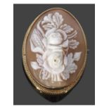 Carved cameo brooch of oval form depicting a floral spray, framed in a yellow metal mount (tested