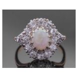 Opal and diamond cluster ring centring an oval shaped cabochon opal, multi-claw set and raised above