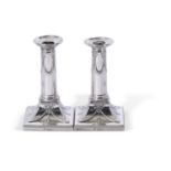Pair of Victorian silver encased dressing table candlesticks, having beaded square loaded bases