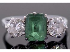 Emerald and diamond three stone ring, the emerald 8.21 x 5.8 x 2.64mm, flanked by two round