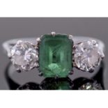 Emerald and diamond three stone ring, the emerald 8.21 x 5.8 x 2.64mm, flanked by two round