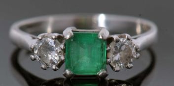 Platinum emerald and diamond three stone ring, the square shaped emerald flanked by two round