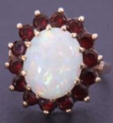 9ct gold opal and garnet cluster dress ring, the opal 12.13 x 9.9mm, raised above a surround of 12