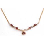 Garnet and diamond pendant/necklace set with five graduated oval cut garnets highlighted with four