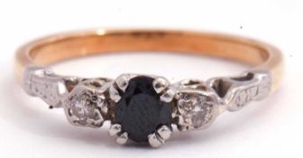 Sapphire and diamond three stone ring centring a round faceted dark sapphire flanked by small