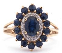 Modern sapphire and diamond cluster ring centring an oval shaped sapphire with a small sapphire