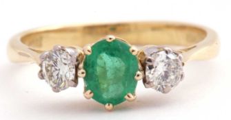 18ct gold emerald and diamond three stone ring, the oval cut emerald flanked by two brilliant cut