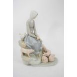 Lladro figure of a girl seated on rockwork surrounded by piglets, 28cm high