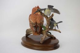 Large model of an owl on a branch with two birds