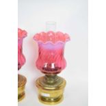 Pair of oil lamps with red vaseline type shades and brass reservoirs, 37cm high (2)