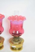 Pair of oil lamps with red vaseline type shades and brass reservoirs, 37cm high (2)