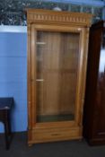 Continental light oak bookcase or display cabinet, moulded cornice over a single glazed door,