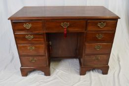 George III mahogany kneehole desk, the body with nine drawers and a central door fitted with brass