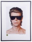 DAVID BOWIE Head and shoulders portrait of the artist in sunglasses. Measures 21 by 14.5”. Denis O’