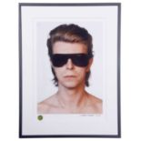 DAVID BOWIE Head and shoulders portrait of the artist in sunglasses. Measures 21 by 14.5”. Denis O’