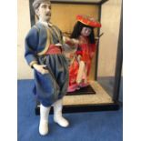 A glass and wooden cased oriental figure of a lady in costume , and another of a gentleman in