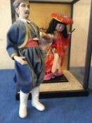 A glass and wooden cased oriental figure of a lady in costume , and another of a gentleman in