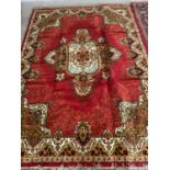 Modern red ground rug with cream, red and green border, central cream motif with green and cream
