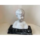 A white marble bust of a smiling boy on a black and white veined marble plinth, 42cmH (condition