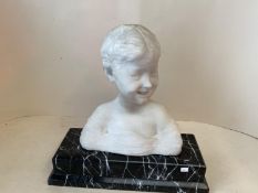 A white marble bust of a smiling boy on a black and white veined marble plinth, 42cmH (condition