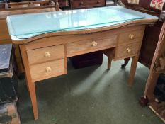 A Limed oak serpentine front dressing table of 5 drawers beneath a plate glass top with curtain rail