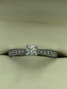 Platinum & diamond ring with central 4 claw set solitaire diamond with single cut diamond shoulders,