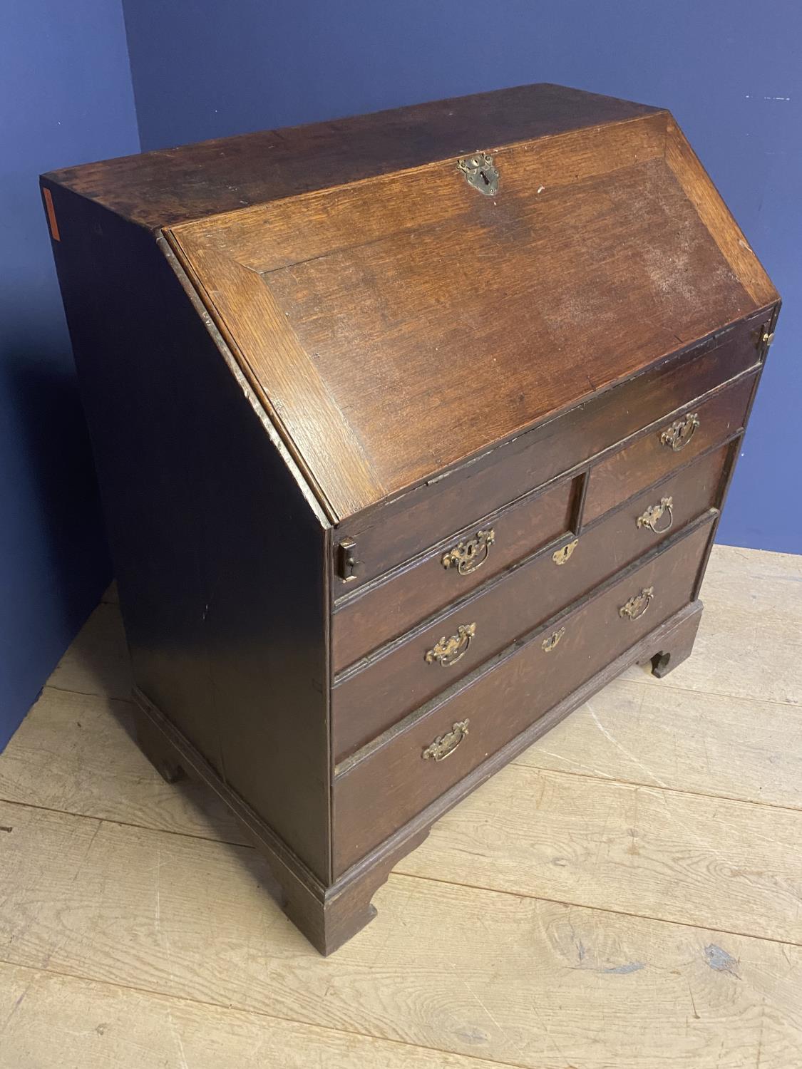 C18th oak bureau of 2 short over 2 long drawers with stepped fitted interior around a well with