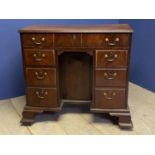 George III figured mahogany kneehole writing desk of 7 drawers with brass drop handles flanking a