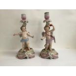 Pair of C19th Rudolstadt porcelain candlesticks, decorated with cherubs on naturalistic swagged,