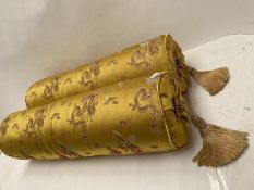 Pair of yellow brocade upholstered bolster cushions, with tassels