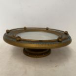 A gilt edged tazza, the white bowl surrounded by a brass galleried edge with blue decoration