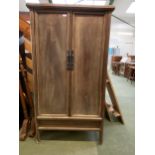 A teak style cupboard on stand, with the cupboard doors opening to reveal shelves and drawers 173 cm