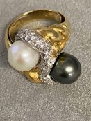 An impressive 18ct gold black and white pearl cross over ring, with central band of platinum mounted