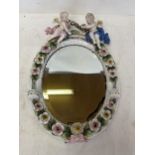 A pair of circular hanging wall mirrors set in a ceramic oval frame with floral decoration