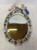 A pair of circular hanging wall mirrors set in a ceramic oval frame with floral decoration